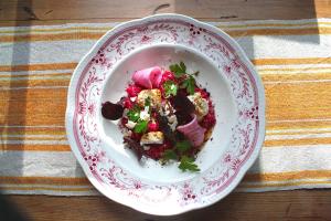 a white plate with a salad on a table at Vallåsens Värdshus STF Hostel in Våxtorp
