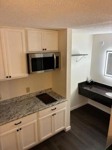 a kitchen with white cabinets and a microwave at Suite Stay in Talladega +3 photos