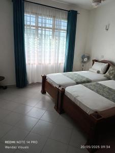 ein Schlafzimmer mit zwei Betten und einem Fenster in der Unterkunft Boutique Apartment in Nyali B6 in Mombasa