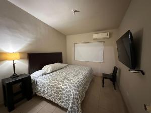 a bedroom with a bed and a flat screen tv at San Basilio Suites in Mexicali