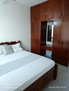 ein Schlafzimmer mit einem großen Bett und Holzschränken in der Unterkunft Boutique Apartment in Nyali B6 in Mombasa