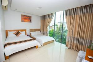 two beds in a room with a large window at Ruby Star Hotel Apartment in Vung Tau +24 photos