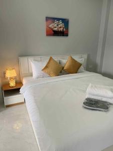 ein weißes Bett mit Kissen und ein Gemälde an der Wand in der Unterkunft Borrii House โบ ลี่ เฮาท์ in Layan Beach