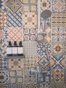 a bathroom with a tile wall with three bottles ofgars at 睡得好Sleepillowell in Hualien City