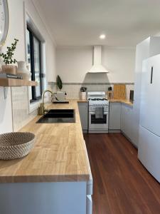 a large kitchen with white appliances and wooden floors at The Little Beach Retreat - Relaxing family sized home one street from the sea! in Port Willunga +19 photos