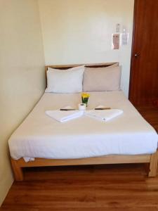 a bed with two towels and a cup and flowers on it at Avelina Inn in Siquijor