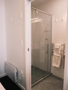 een douche met een glazen deur in een badkamer bij The Urban Nest in Wellington