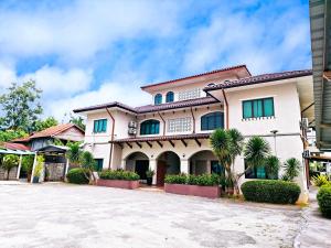 a large white house with green windows at Villa 223 in Kajang
