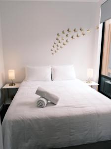 een wit bed met een handdoek erop bij The Urban Nest in Wellington