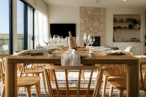 een eetkamer met een houten tafel met wijnglazen bij Coast in Stokes Bay