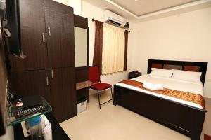 une chambre avec un lit et une chaise rouge dans l'établissement Karuna Regent, à Chennai