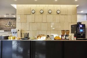 a kitchen with a counter with clocks on the wall at Hoteld Benikea in Osan