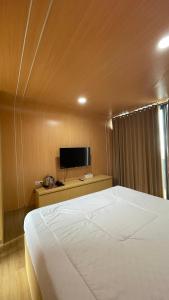 a bedroom with a large white bed and a television at The Lakebox Menjer by Travelink in Garung