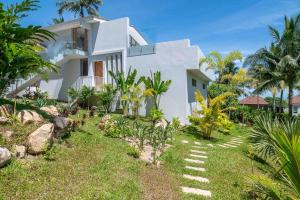 une maison blanche avec un jardin en face dans l'établissement 4br Villa Breeze Tropical Sea View Retreat, à Ban Bang Po