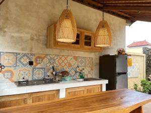 a kitchen with a black refrigerator and two pendant lights at Kapten Nyoman House in Saba +34 photos