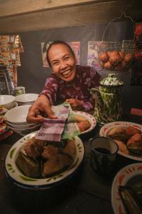 Ein Mann, der an einem Tisch mit Teller Essen sitzt. in der Unterkunft Puri Made Homestay, Ketapang in Ketapang