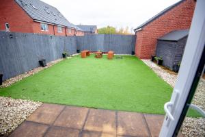 une cour arrière avec une pelouse avec des tables et des chaises dans l'établissement PG Stays - Spacious Rooms with Shared Facilities, à Wigan