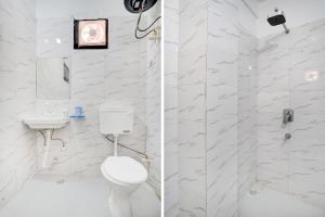 a white bathroom with a toilet and a shower at Collection O Sector 7 Rohini Formerly Giriraj Residency in New Delhi +32 photos