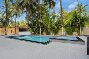 ein Swimmingpool mit Palmen im Hintergrund in der Unterkunft Townhouse Morjim Beach North Goa Formerly Bay Breeze Hotels & Resorts in Chopdem