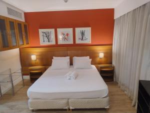 a bed in a room with an orange wall at Hotel Slaviero Grandflats Suíte Master Luxo in Sao Paulo +16 photos