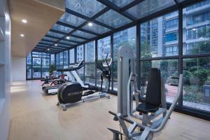 een fitnessruimte met cardio-apparatuur in een gebouw met ramen bij Yongzhou Chuang Fa Cheng XiaoXiangYi Hotel in Guzhuting