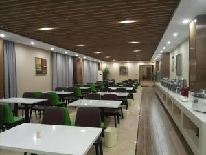 a dining room with tables and green chairs at GreenTree Inn Xuancheng Jingxian Wannan First Street Express Hotel in Jingxian