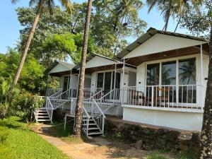 a white house with palm trees in front of it at Ourem Palace in Palolem
