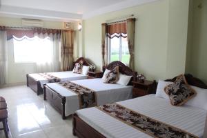 Thach LoiにあるHotel Kien Ngaのベッド3台と窓が備わるホテルルームです。