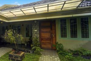 a house with a wooden door in the yard at Super Collection O Chalakkudy River Annamanada Formerly Svasthya Retreat in Māla