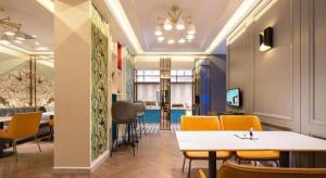 Una habitación con sillas amarillas y una mesa dentro. en Magnotel Hotel Dandong Railway Yalv River, en Dandong