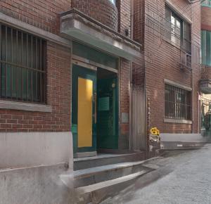 ein Eingang zu einem Backsteingebäude mit einer gelben Tür in der Unterkunft Nldam Stay Seoul Station Walk 8min Near Namsan Tower, Easy to Hongdae, Myeongdong,DDP in Seoul