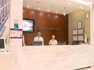 twee mensen aan een balie in een lobby bij City Comfort Inn Guangzhou Zengcheng Yonghe Yongkang Road in Yonghe