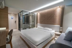 ein Schlafzimmer mit einem großen weißen Bett und ein Badezimmer in der Unterkunft Bluphere Residence by Prop Hopper in Na Jomtien