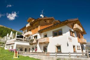 a large white building with a wooden roof at Hotel Alegra in Livigno