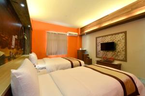 台中的住宿－西悠飯店台中店，橙色墙壁的酒店客房内的两张床