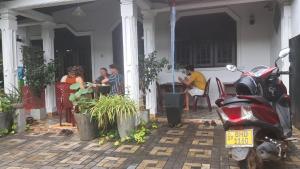 a group of people sitting at a table on a porch at Indunil Family Residence With Pool Hiriketiya in Dickwella +3 photos
