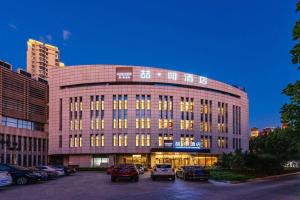 Un gran edificio con coches aparcados en un estacionamiento. en James Joyce Coffetel Tianjing First Central Hospital Nankai University, en Tianjin