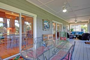 un porche cubierto con mesa de cristal y sillas en OG02: 2 Ocean Green, en Kiawah Island