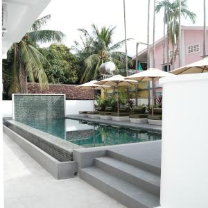 a pool with stairs and umbrellas in a building at Serenity Angkor in Phum Pobos