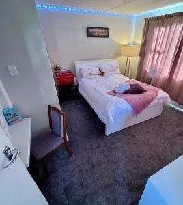 a small bedroom with a bed and a chair at Casa Carterton in Carterton