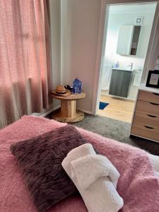 a bedroom with a bed with a pink blanket and a table at Casa Carterton in Carterton