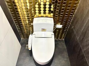 ein Badezimmer mit Toilette und einer goldenen Akzentwand in der Unterkunft KGH Villa Rental in Cuayan