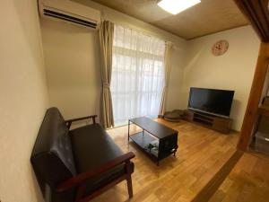 ein Wohnzimmer mit Sofa und Flachbildfernseher in der Unterkunft あかり庵 in Iki