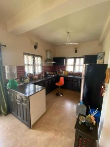 a large kitchen with black cabinets and a red stool at 2 Bedroom furnished flat in Iskcon Mayapur in mayapur