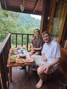 un homme et une femme assis à une table sur une véranda dans l'établissement Diyaluma View Cotage, à Koslanda 68 autres photos