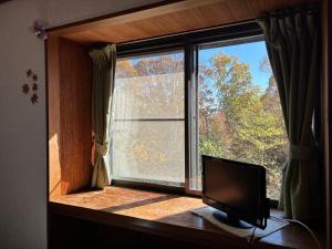 a window in a room with a television in front of it at ペンションとも in Nosakada