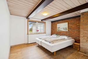 een slaapkamer met een bed en een bakstenen muur bij Country Stay In Cosy Farmhouse With Horses in Bøvlingbjerg
