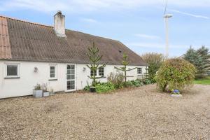 een wit huis met een zwart dak bij Country Stay In Cosy Farmhouse With Horses in Bøvlingbjerg