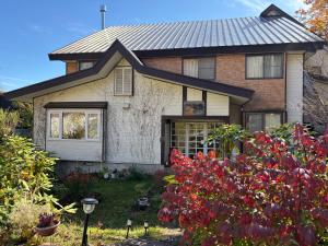 a house with red flowers in the front yard at ペンションとも in Nosakada