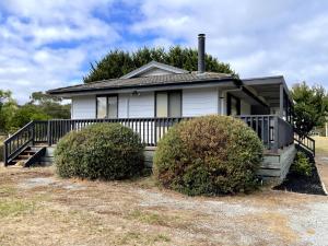 a white house with a porch and two bushes at Shelby s Lodge in Evergreen